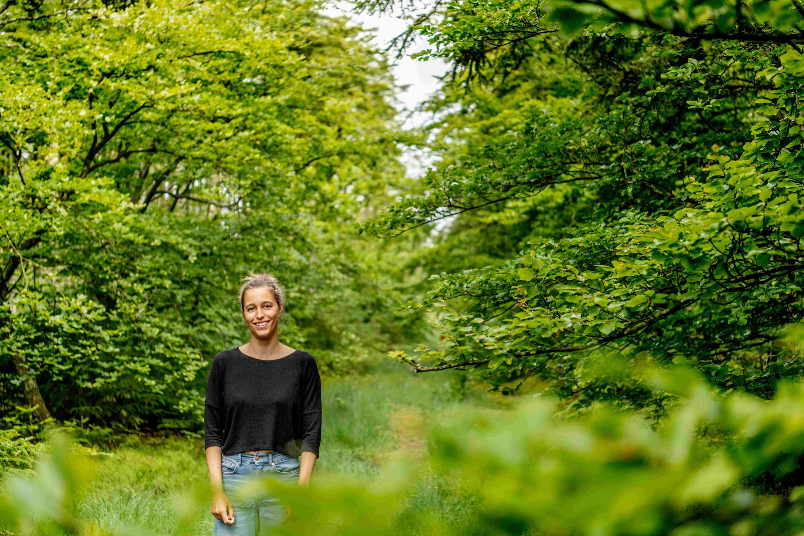 Lächelnde Frau im schwarzem Shirt in grünem Wald